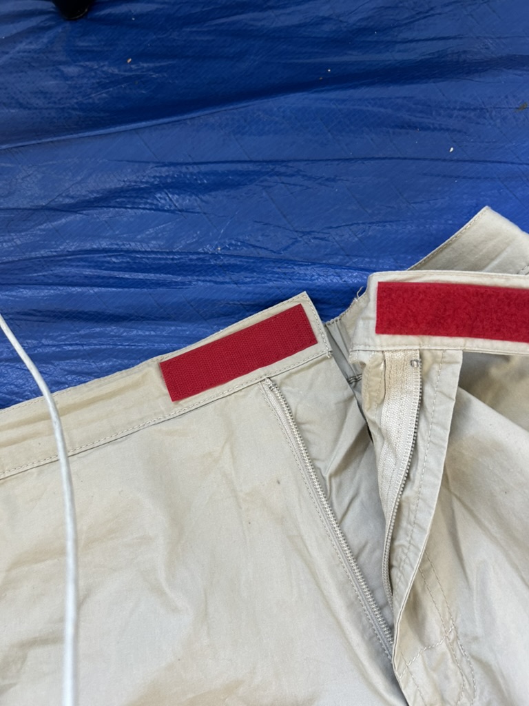 White work pants waistband detail — red velcro tabs